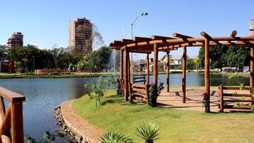 A park with a wooden pergola, a pond, and a fountain.