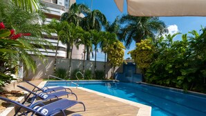 A pool area with lounge chairs, a clear blue pool, and surrounding tropical vegetation. - Radisson Hotel Anapolis (Anapolis)