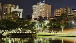 A high-rise hotel with multiple floors, a flag on top, and a reflection in the water. - Radisson Hotel Anapolis (Anapolis)