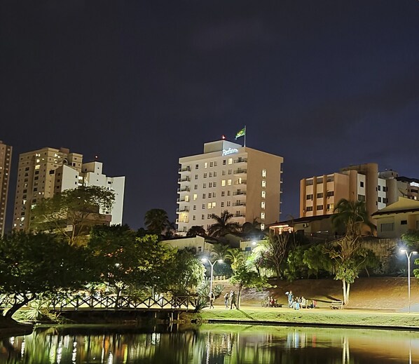 A high-rise hotel with multiple floors, a flag on top, and a reflection in the water. - Radisson Hotel Anapolis (Anapolis)