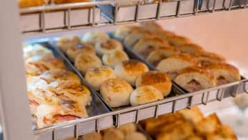 A display of various baked goods, including bread rolls and pastries, arranged on metal racks.
