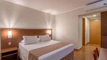 A hotel room with a large bed, bedside table, and a wooden headboard.