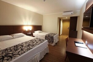 Habitación de hotel con dos camas, un escritorio y una televisión.
