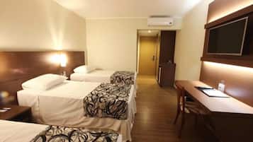 A hotel room with two beds, a desk, and a TV.