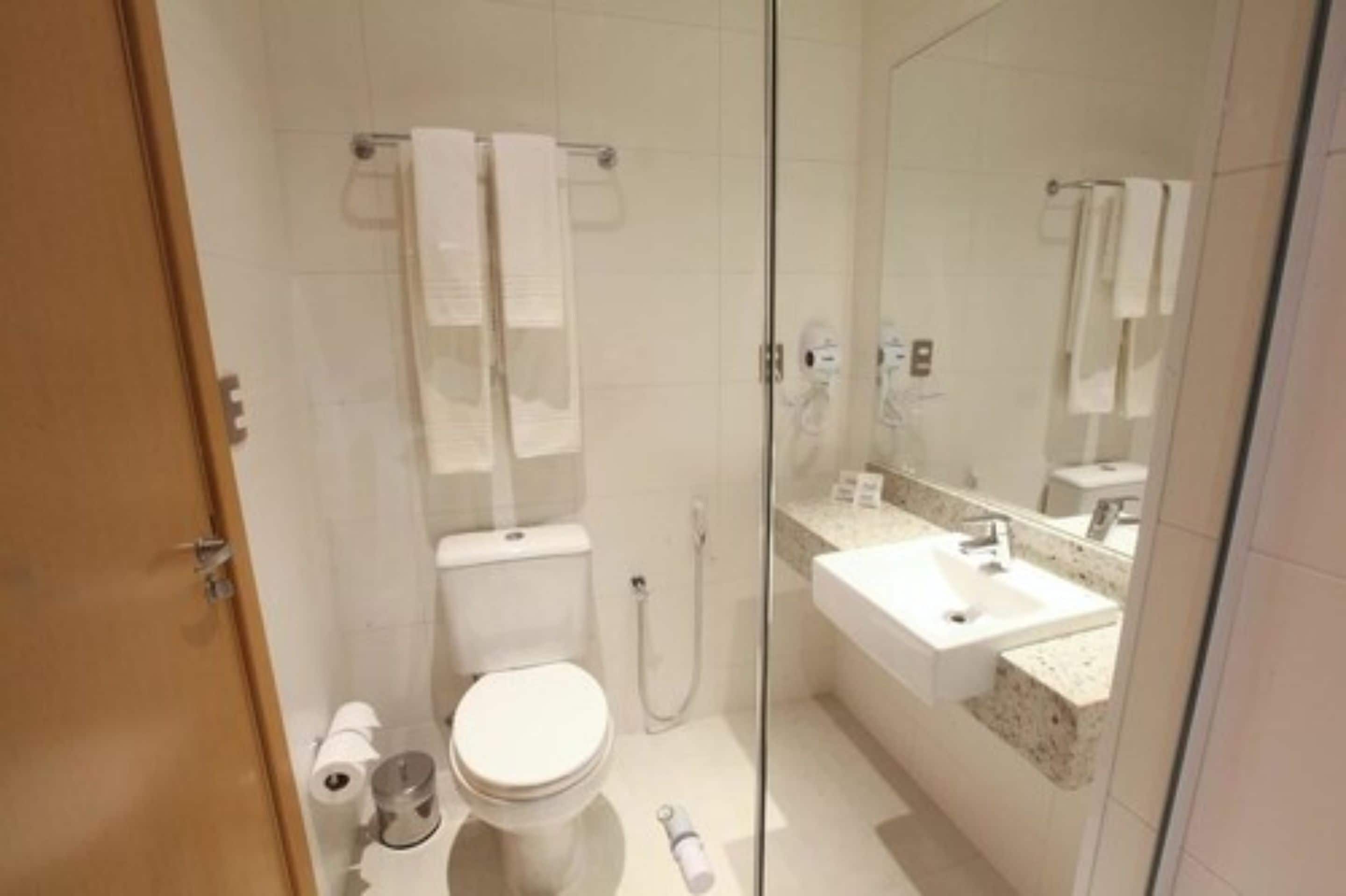 A modern bathroom with a toilet, shower, and sink.
