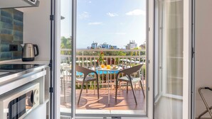 A kitchen with a view of a balcony, a table with chairs, and a pool area. - Residence Villa Giardini (Giardini Naxos)
