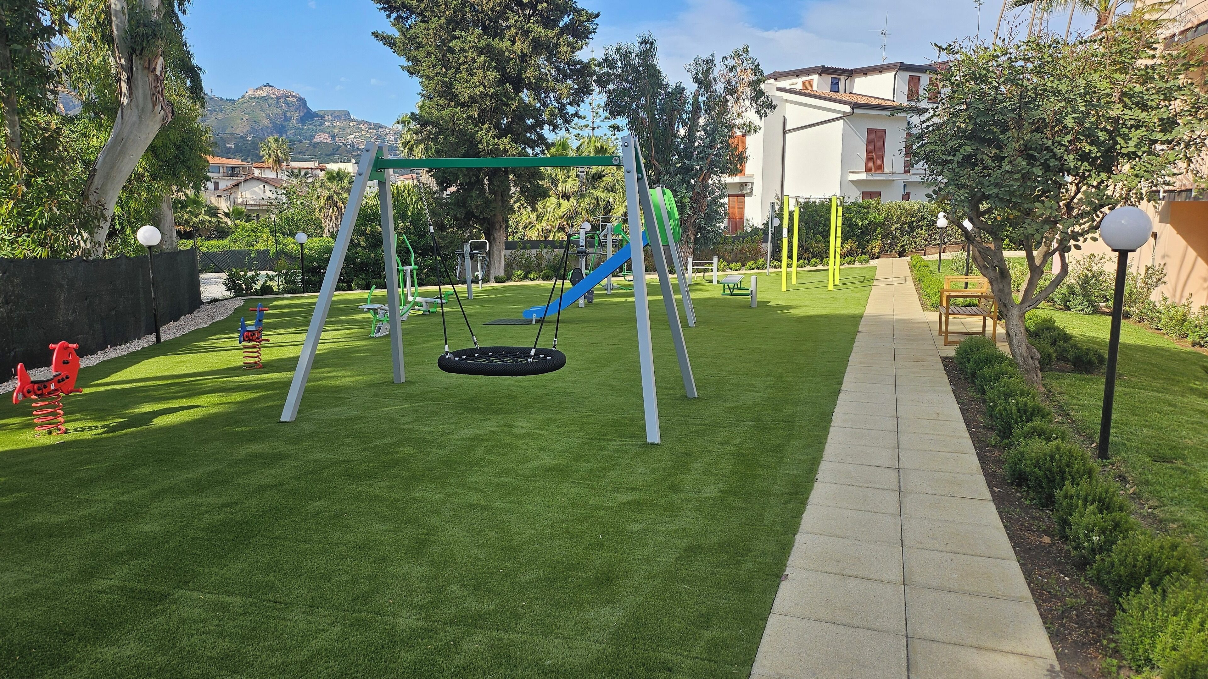 A well-maintained playground with swings, a slide, and exercise equipment.