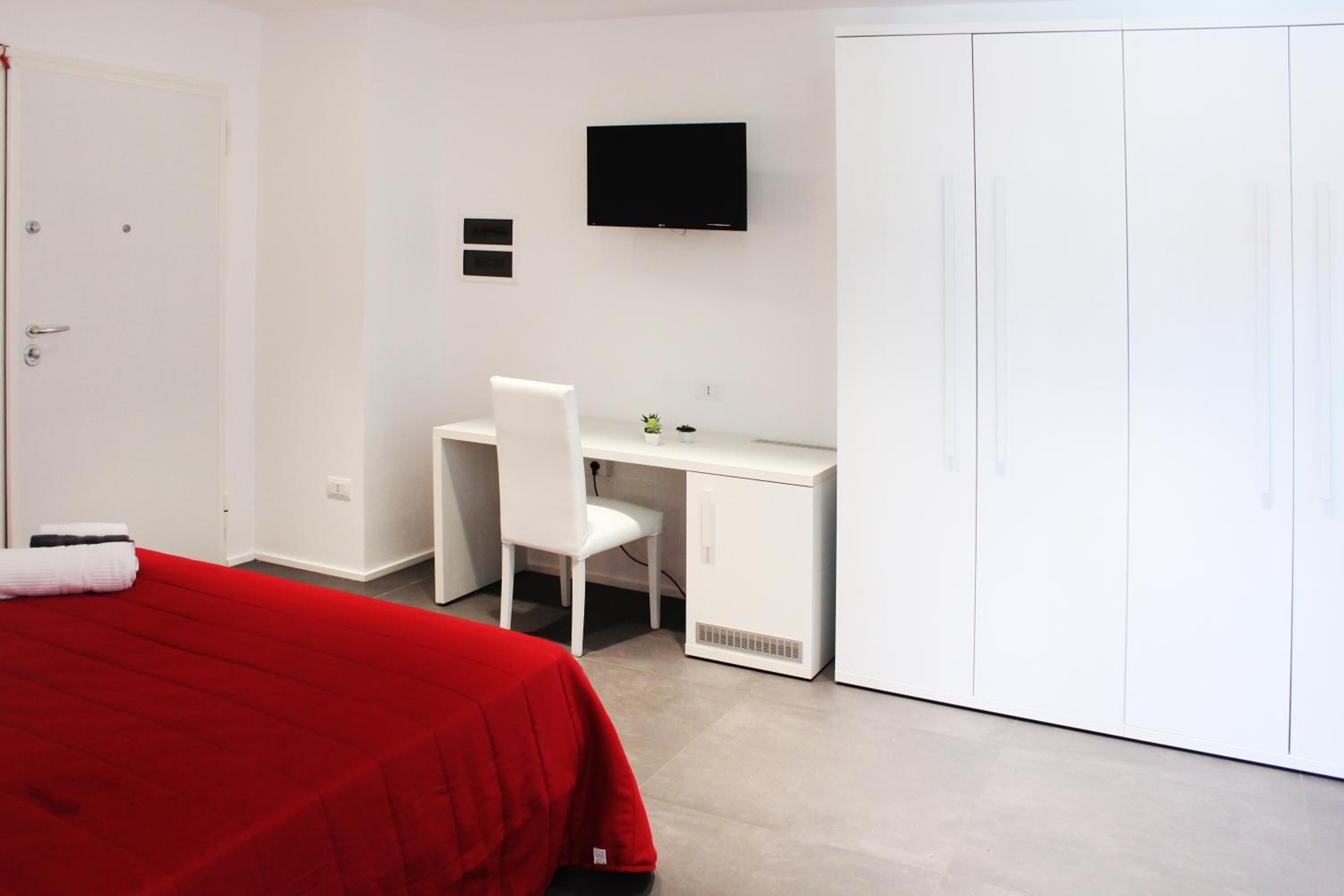 Une chambre d’hôtel équipée d’un lit, d’un bureau, d’une chaise, d’une télévision et d’une armoire.