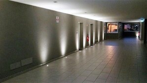 En lång, smal hall med ett klinkergolv och en rad dörrar på ena sidan.