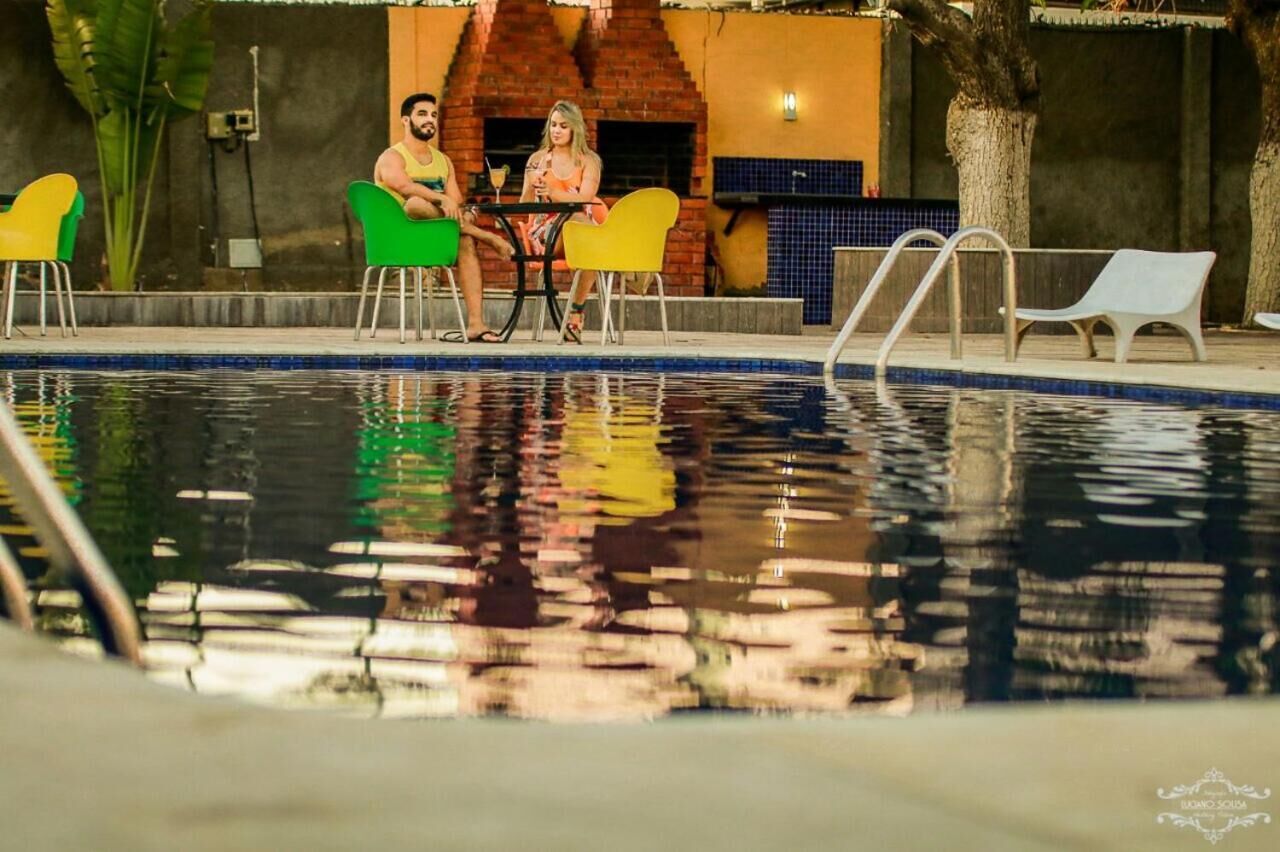 A pool area with a brick structure, chairs, and a table.