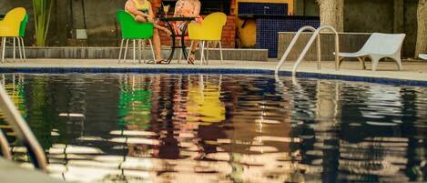 A pool area with a brick structure, chairs, and a table.