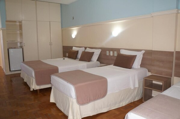 Una habitación de hotel con dos camas, un armario y una mesita de noche pequeña.