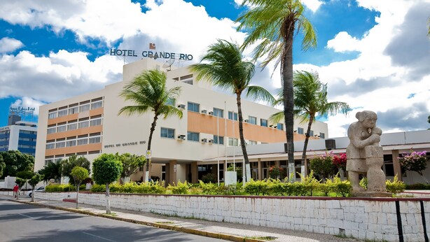 A hotel named 'Hotel Grande Rio' with a modern architectural design, palm trees, and a statue in the foreground. - Hotel do Grande Rio (Petrolina)
