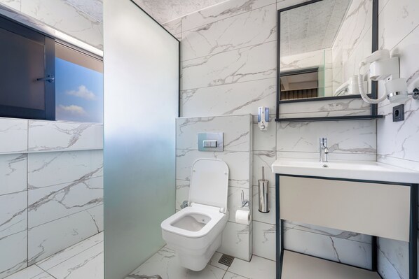 A modern bathroom with a toilet, sink, and mirror. - Lemon Hotel (Konyaalti)