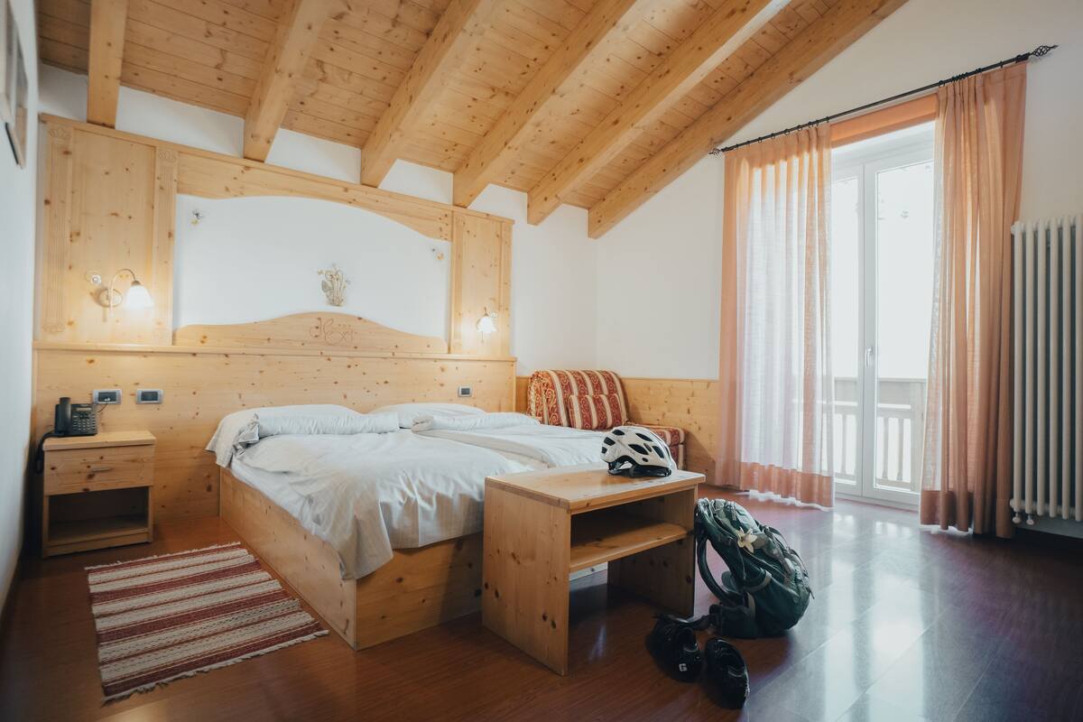 A wooden bedroom with a bed, bedside table, and a small desk.