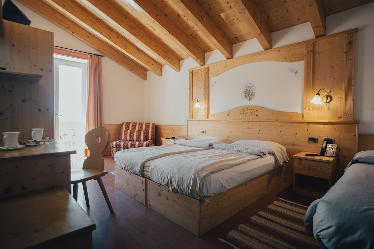A wooden bedroom with two beds, a desk, and a chair.