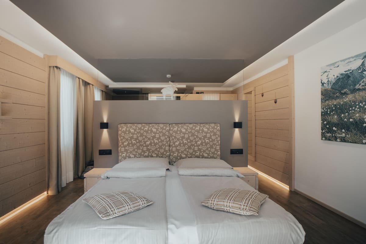 A modern bedroom with a large bed, wooden panel walls, and a ceiling light.
