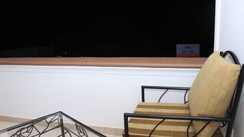 Une pièce d’angle avec une fenêtre, une chaise et une table en verre.