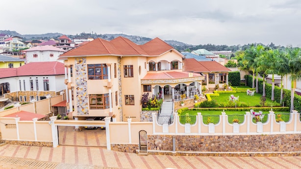 A large, multi-story house with a well-maintained garden, a stone wall, and a paved driveway. - Mountain's View Hotel (Bujumbura)