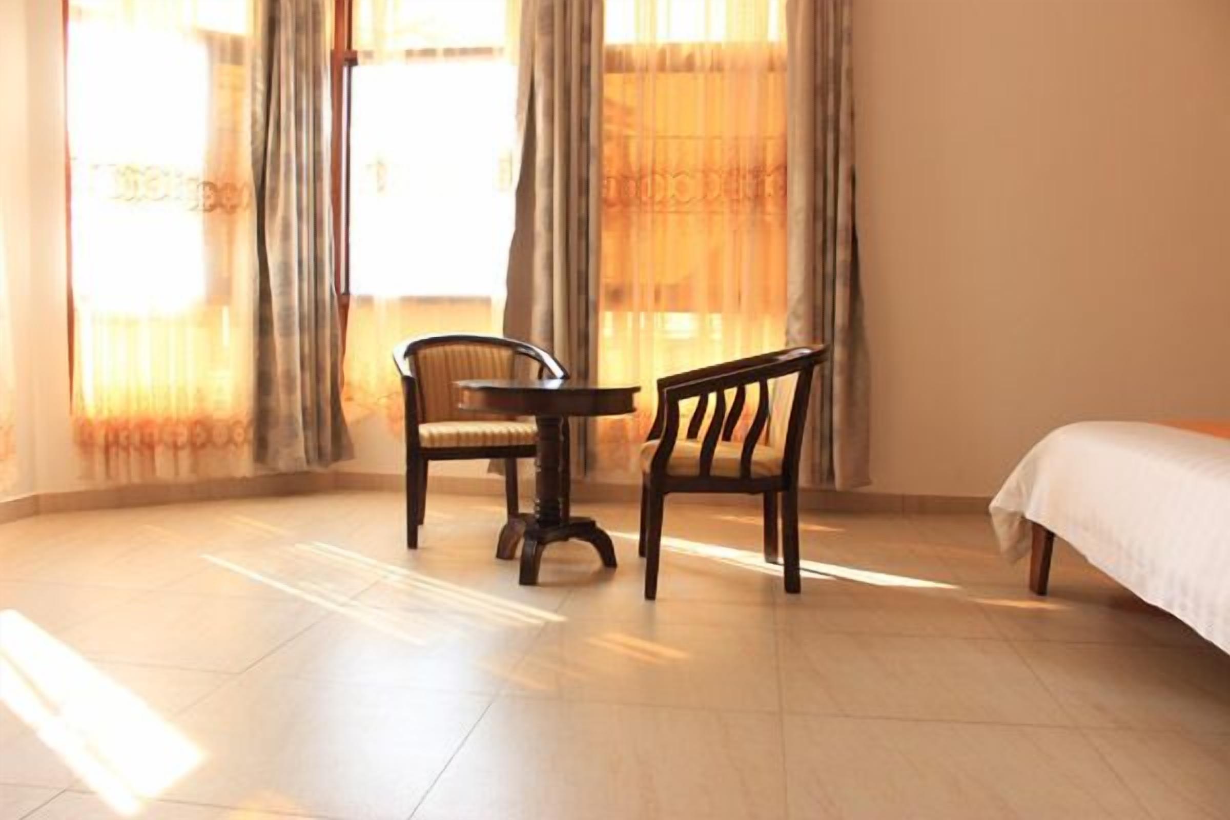A room with a bed, a round table, and two chairs.