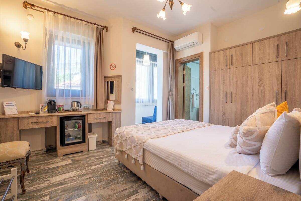 Ein Hotelzimmer mit Bett, Schreibtisch mit Computer, einem kleinen Kühlschrank, Fernseher und Kleiderschrank.