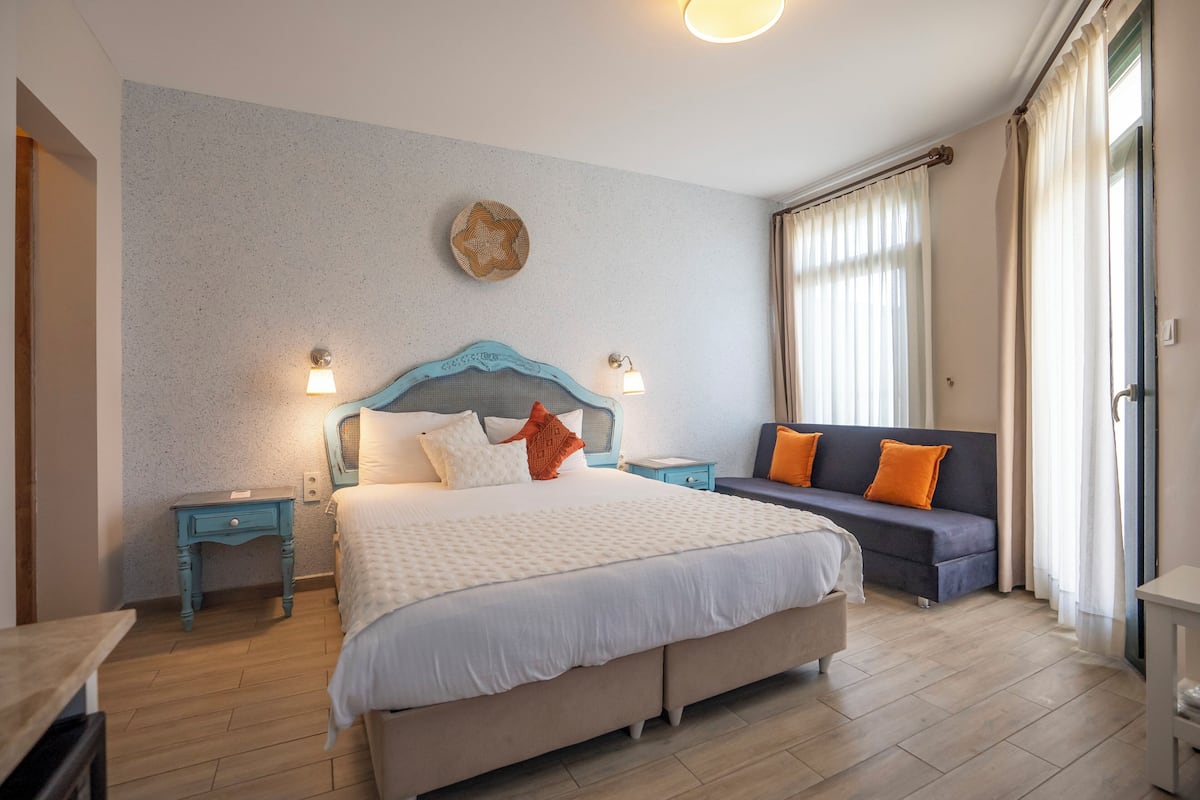 Ein Schlafzimmer mit einem großen Bett, einer Couch, einem Nachttisch und einer Wandlampe.