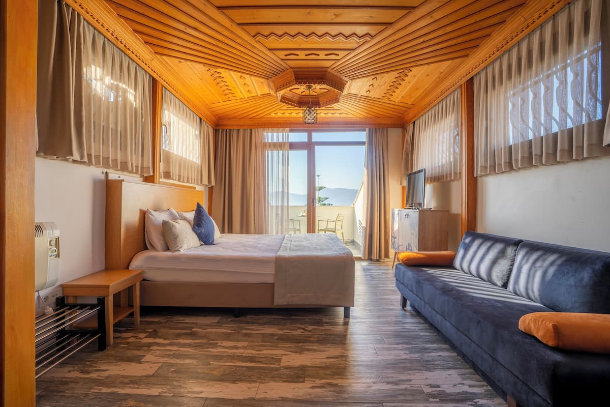 Ein Hotelzimmer mit Bett, Sofa, Fernseher und Blick ins Freie.