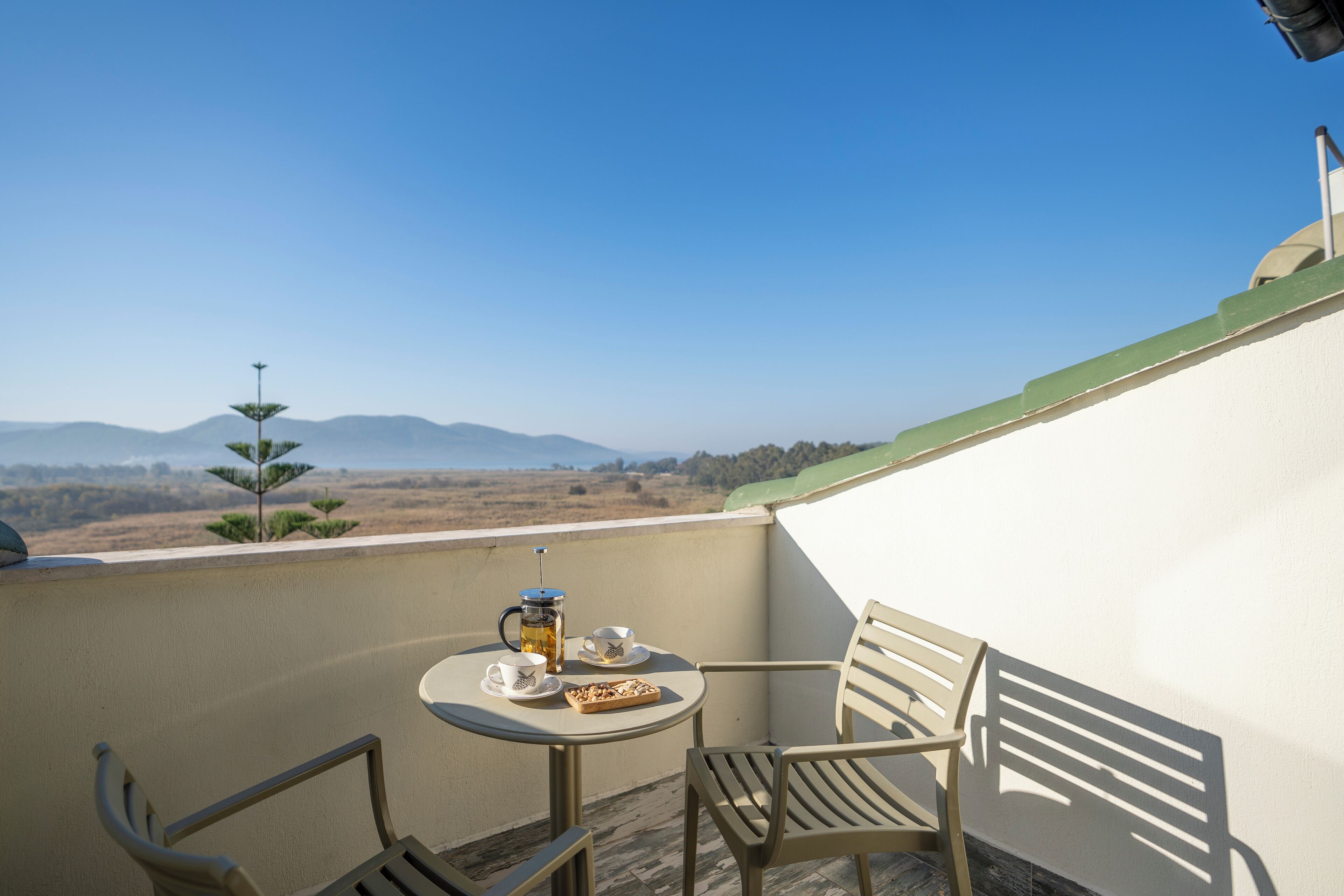 Un balcon avec une table, deux chaises et une vue sur les montagnes lointaines.