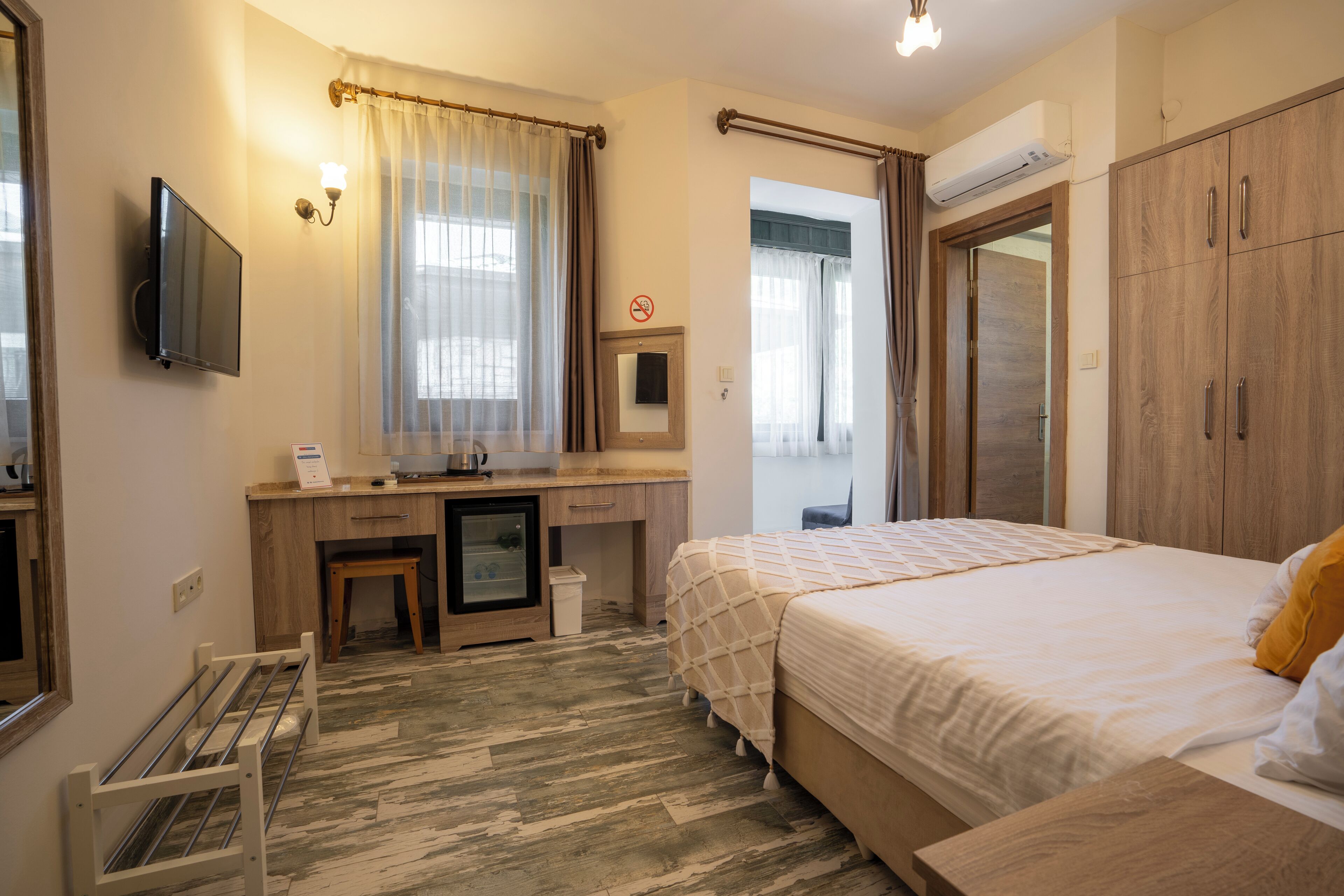 Hotellihuone, jossa on sänky, työpöytä tietokoneella, televisio ja vaatekaappi.
