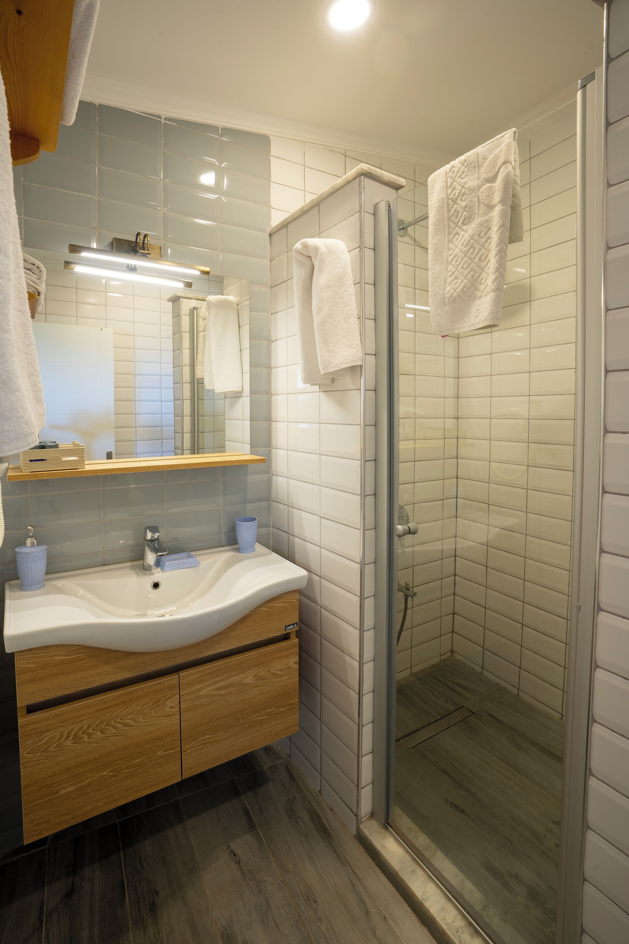 Un baño moderno con cabina de ducha de vidrio, tocador de madera y un espejo grande.