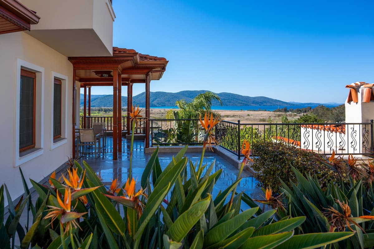 Ein Poolbereich mit Pergola, Gartenmöbeln und tropischer Bepflanzung.