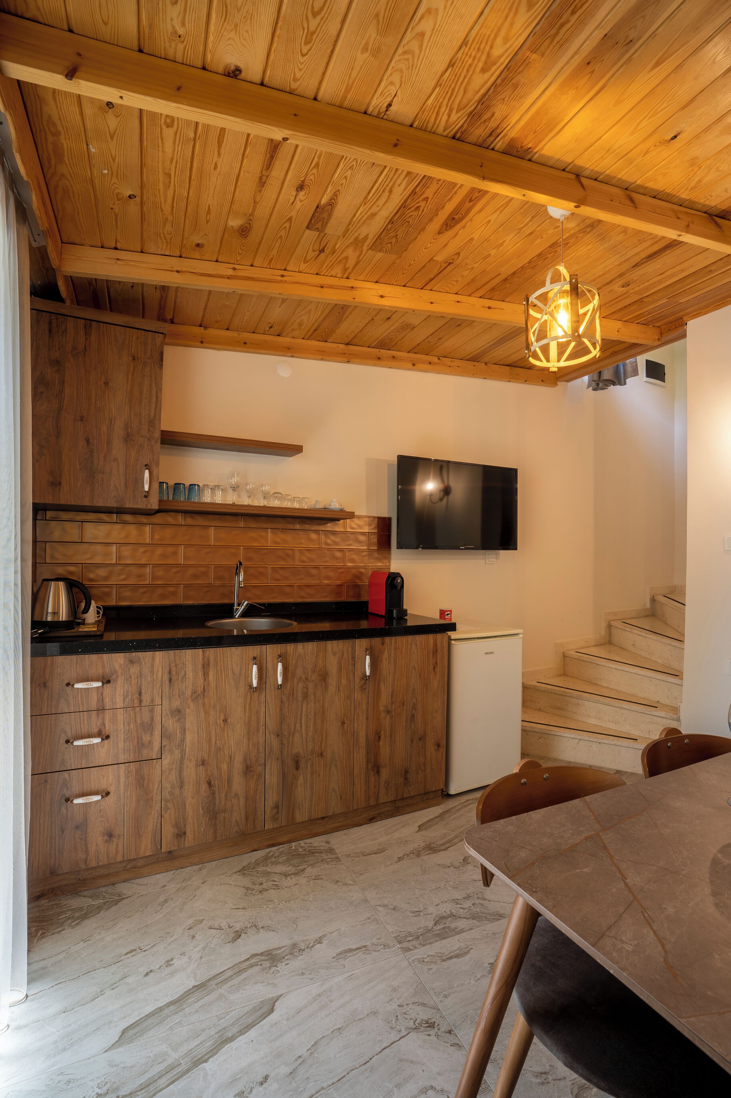 A kitchen with wooden cabinets, a black countertop, a built-in stove, and a small refrigerator.