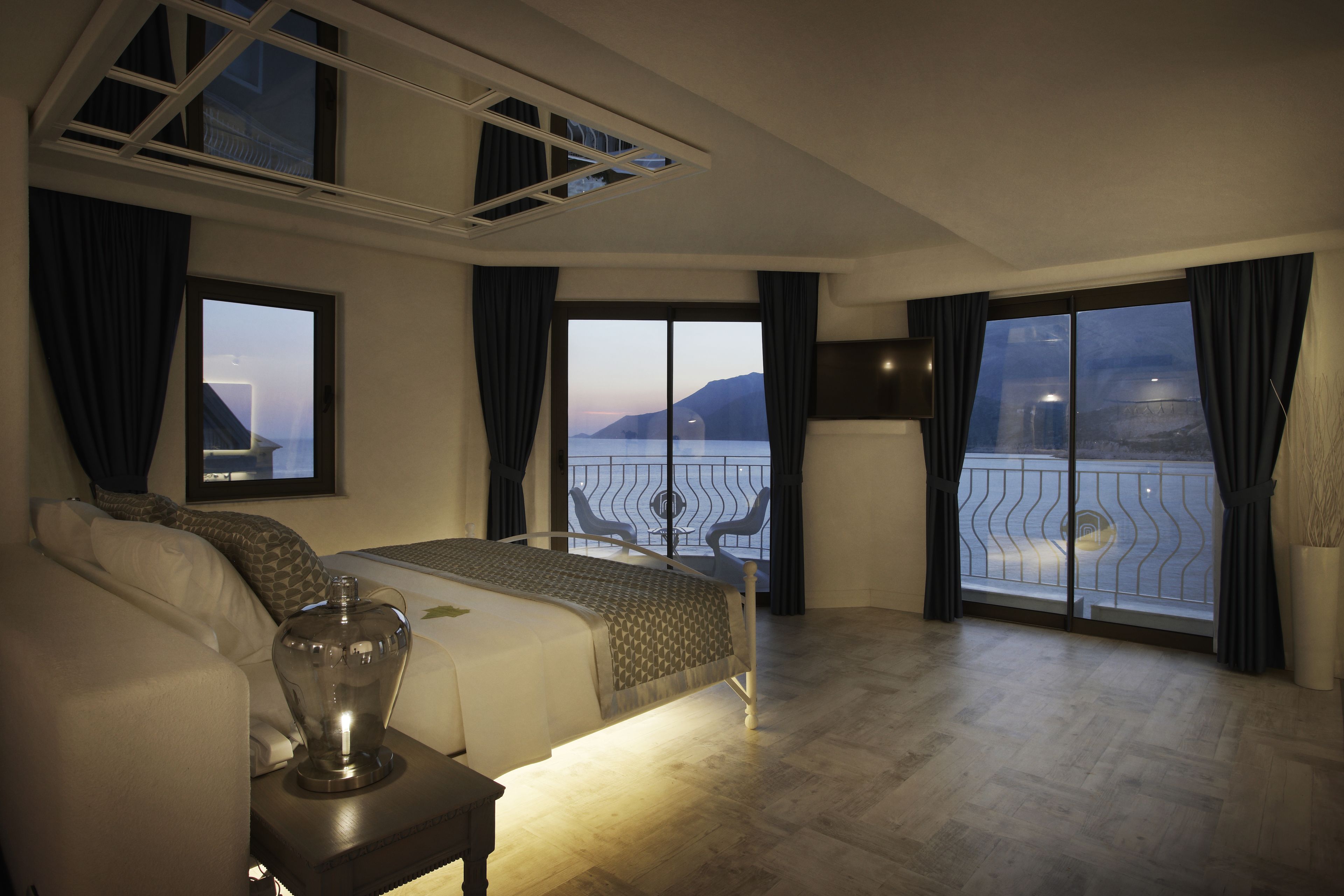 Un dormitorio con una cama grande, una mesita de noche y vistas al mar desde un balcón.