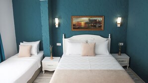 A bedroom with two beds, a large painting on the wall, and two bedside lamps. - Alaçatı 716 Hotel (Cesme)
