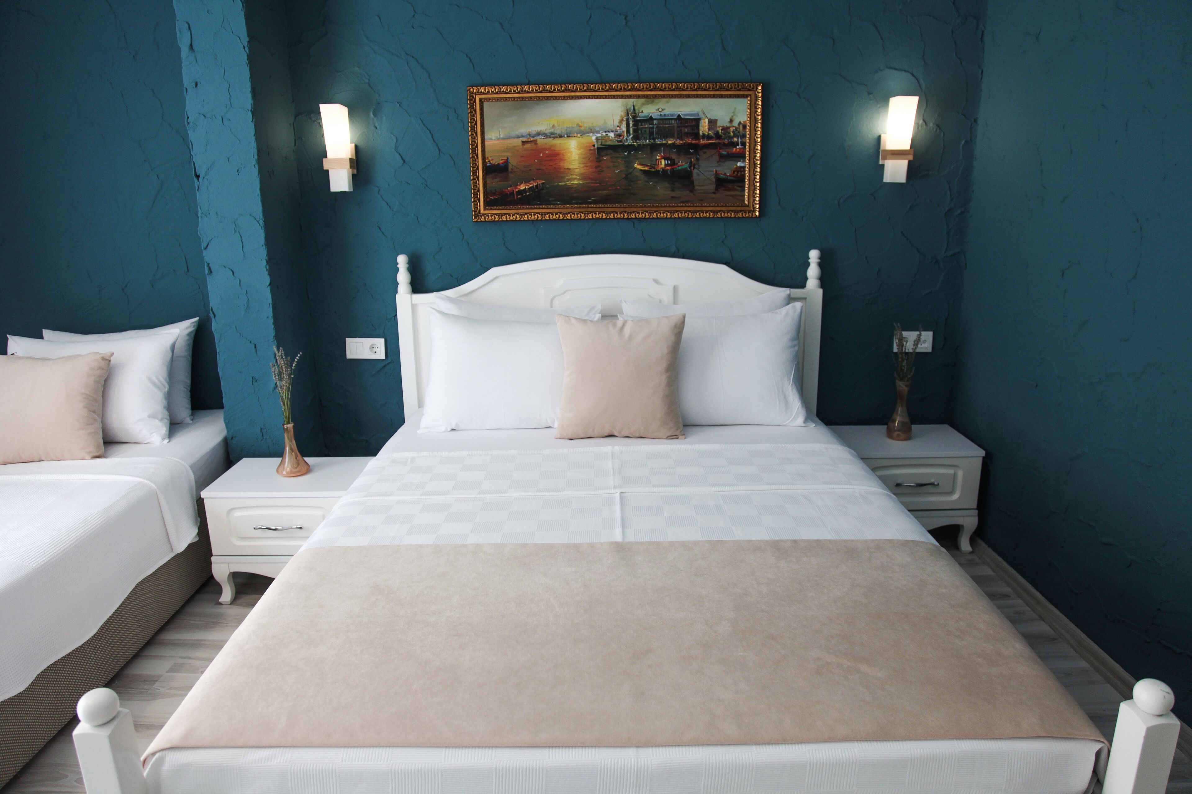 Een slaapkamer met een groot bed, twee nachtkastjes, een bijzettafeltje en een schilderij aan de muur.