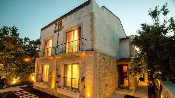 A two-story stone building with a balcony, a staircase leading to the entrance, and a well-lit exterior. - Alaçatı 716 Hotel (Cesme)