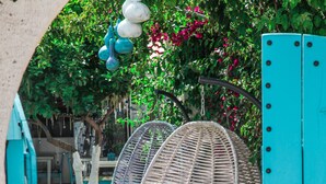 A garden with two wicker swing chairs and a turquoise gate. - Alaçatı 716 Hotel (Cesme)