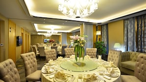 A formal dining room with a round table, upholstered chairs, and a chandelier. - Excemon Yuyao Hemudu Hotel (Ningbo)