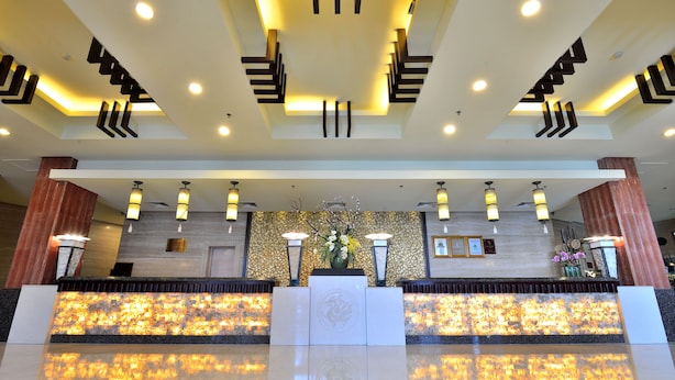 A hotel reception area with a modern design, featuring a central reception desk, decorative lighting, and a decorative wall with a floral arrangement. - Excemon Yuyao Hemudu Hotel (Ningbo)