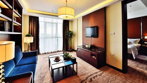 A hotel room with a sofa, a coffee table, a TV, a bed, and a bookshelf. - Excemon Yuyao Hemudu Hotel (Ningbo)