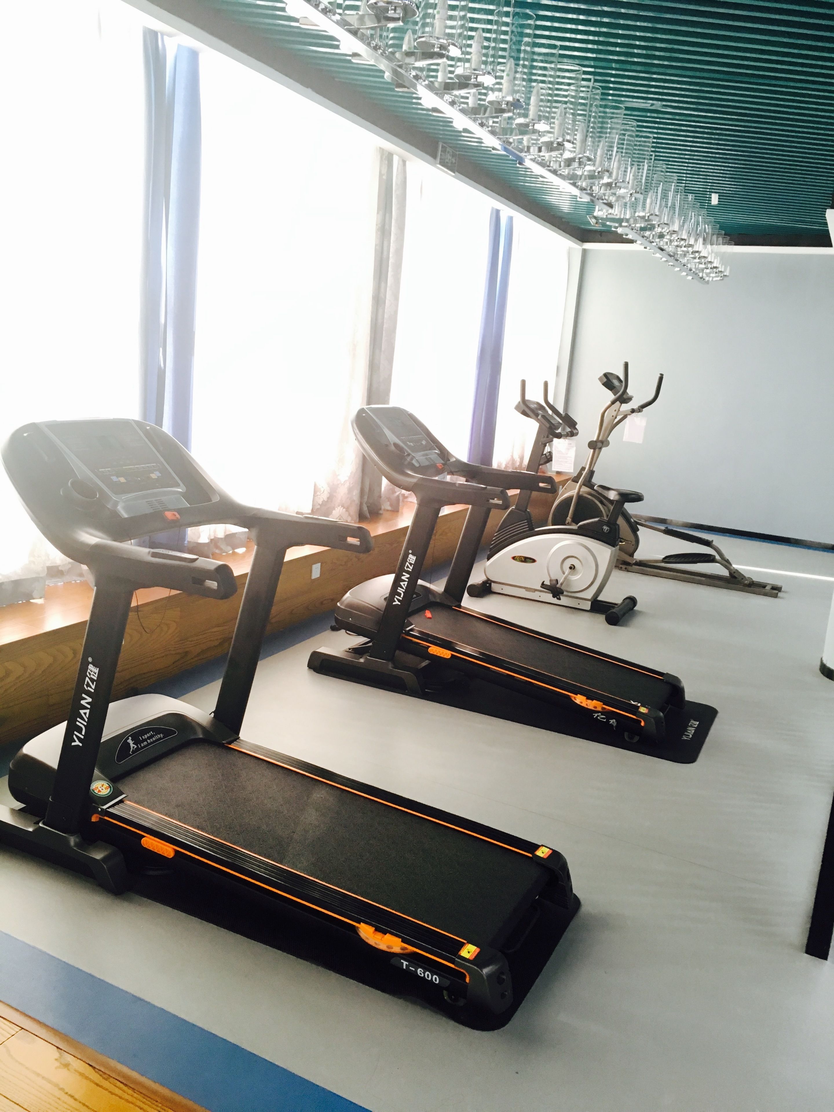 Un gimnasio con equipo de ejercicio, incluyendo cintas de correr y una máquina elíptica.