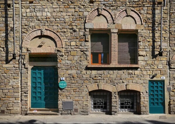 A stone building with arched windows and doors, numbered 7 and 9.