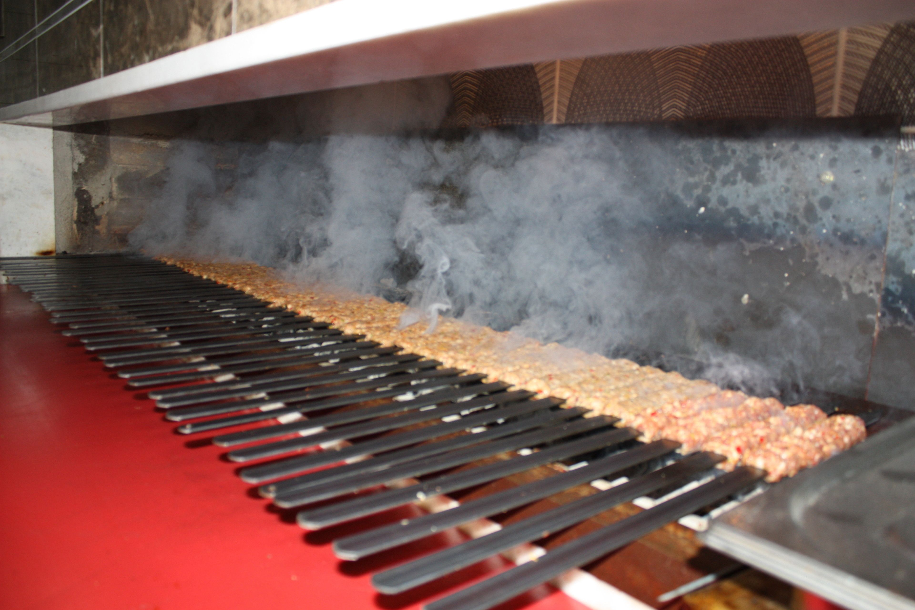 A smoke-filled cooking area with a long grill and a red floor.