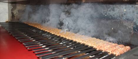 A smoke-filled cooking area with a long grill and a red floor.