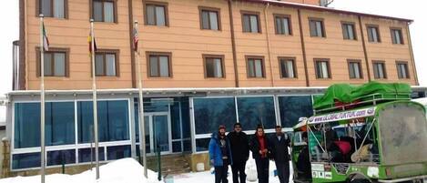 Un edificio con varias ventanas y un vehículo verde estacionado adelante.