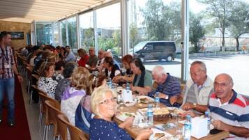 Guests can dine in a spacious communal area with large windows offering views of the outdoor space.