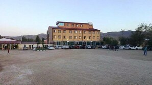 A multi-story building with a flat roof and a parking lot in front. - Butik Ertur Hotel (Dogubayazit)
