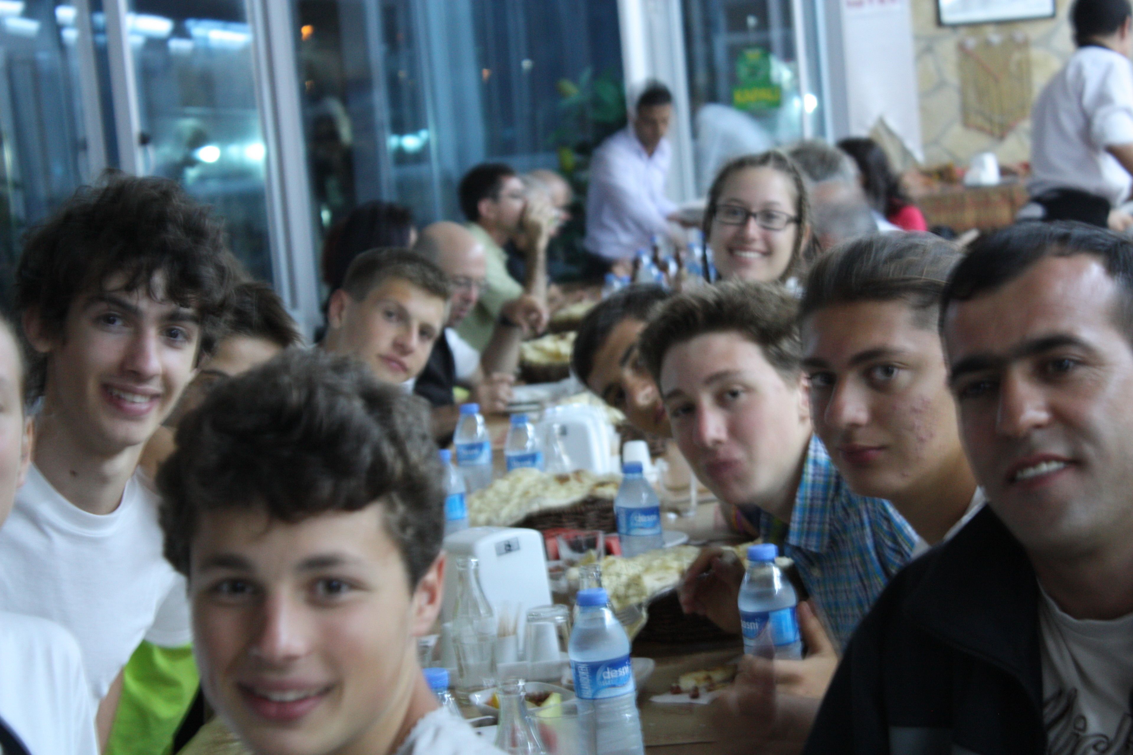 Un grupo de personas sentadas en una mesa en un restaurante, con botellas de agua y un menú.