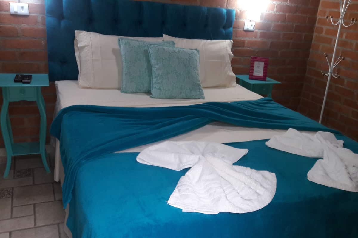 Een hotelkamer met een bakstenen muur, een blauw hoofdeinde en een blauwgroene sprei.
