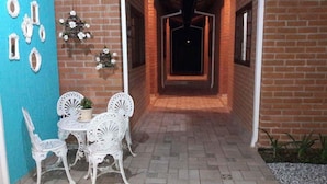 A narrow brick corridor with a tiled floor, leading to a dark interior. - Toca Hospedaria (São Bento do Sapucaí)